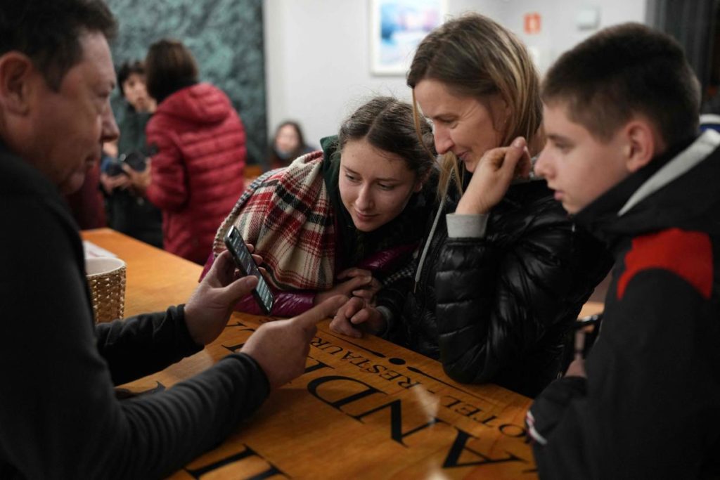 Un chauffeur de taxi traduit un SMS avec son téléphone portable pour communiquer avec une réfugiée ukrainienne et ses enfants, lors d'une halte dans un restaurant en bord de route à Burgos (Espagne), le 16 mars